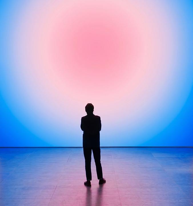 Sillouette van een persoon kijkt naar een roze blauwe gloed op de muur voor hem.